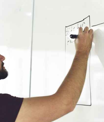 Man planning competitive advantage on whiteboard
